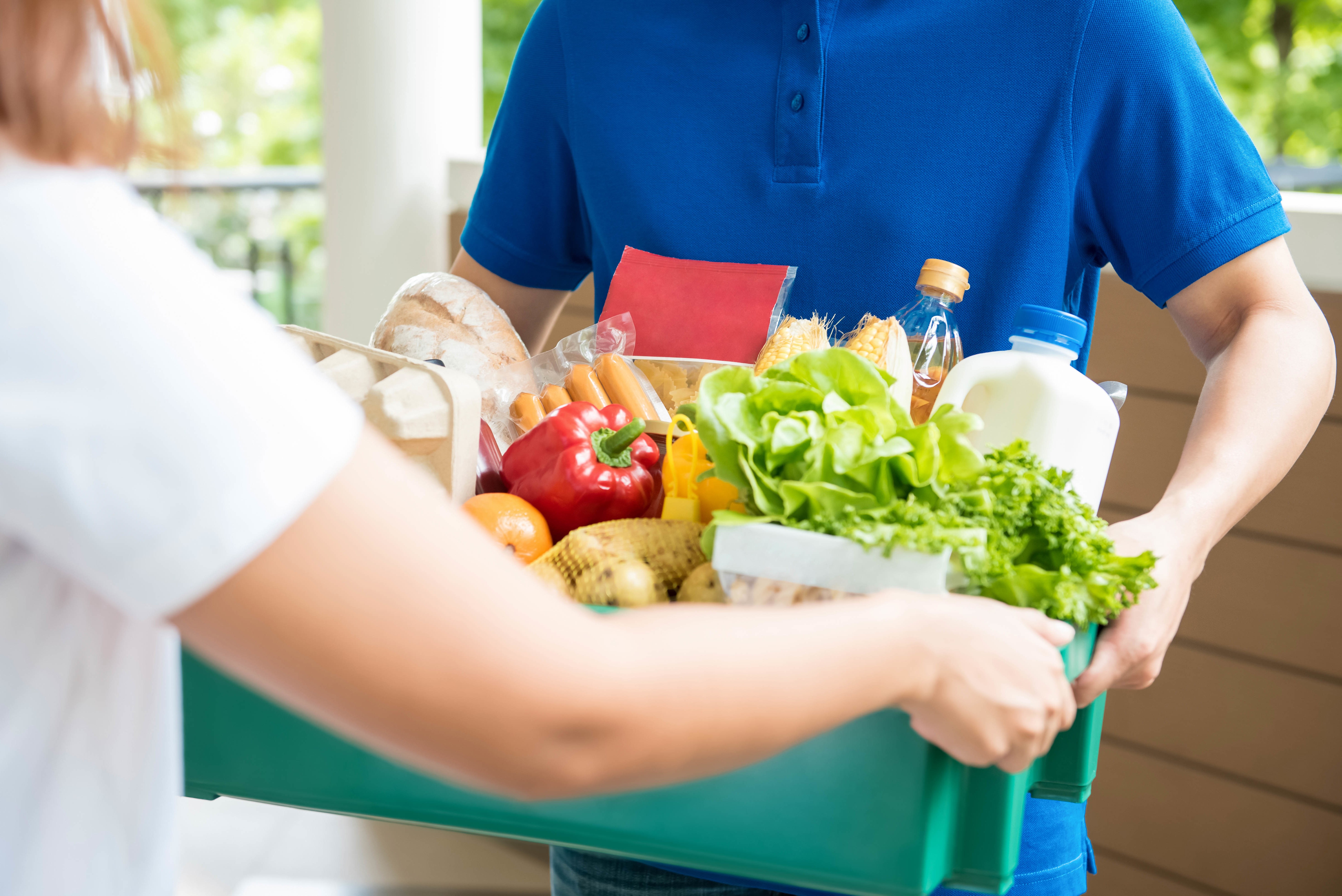 a person is delivering a box of groceries to someone's door