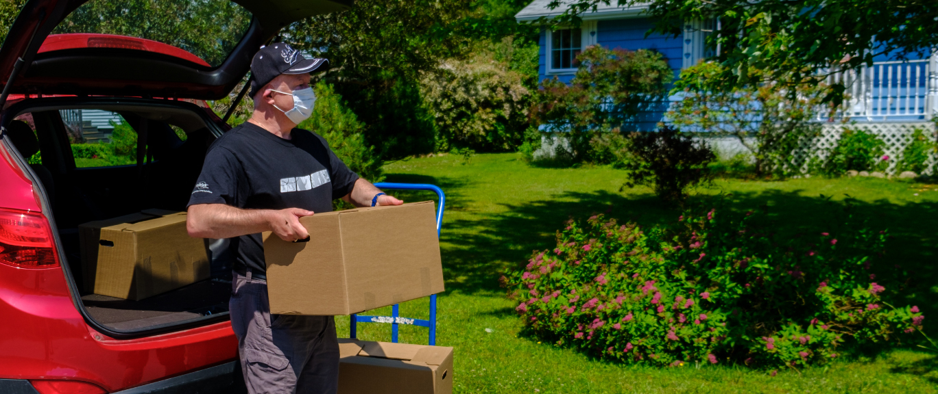 volunteer removing food box from car for home delivery