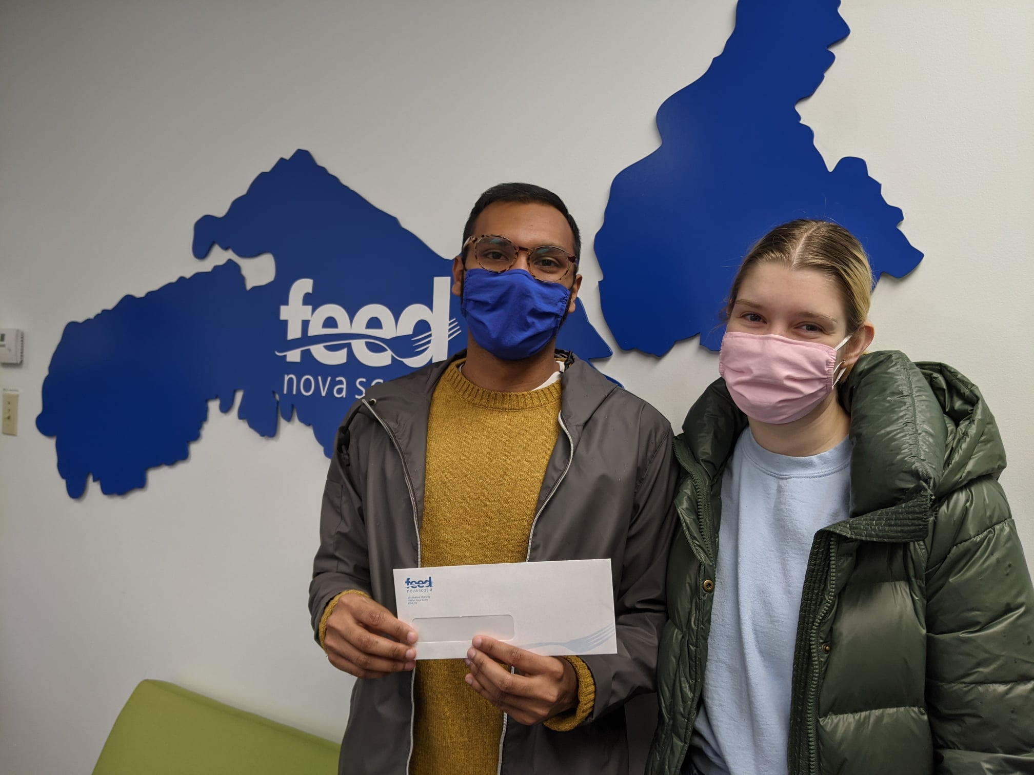 Shahbaz and his girlfriend holding cheque by Feed Nova Scotia sign