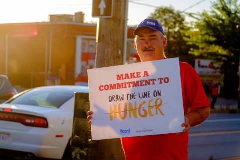 Man holding a placard about hunger awareness