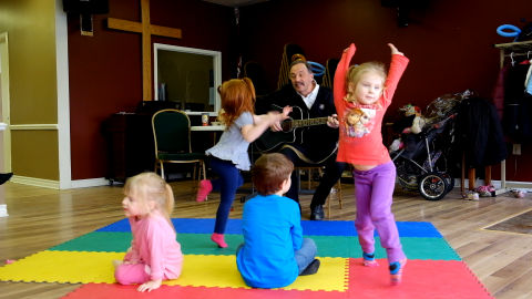 four young children dancing on a colourful mat 