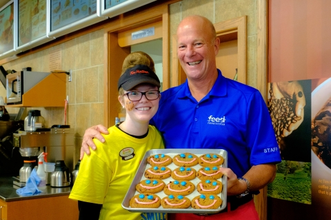 two people smiling holding a tray of chocolate chunk cookies