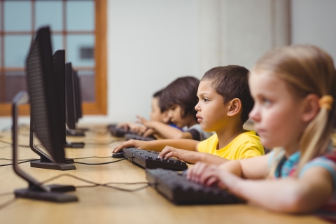 Four children sitting in front of computer screens 