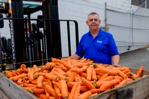 A man standing in front of a crate of carrots