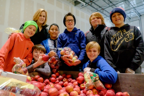 Eight people smiling in front of a crate of apples 