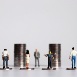 small people figurines standing in front of two piles of coins with their backs to the camera