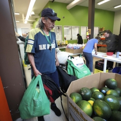 Man standing next to a farm bin of melons 