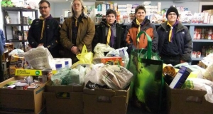 Five scouts stand with bags and boxes of non-perishable food