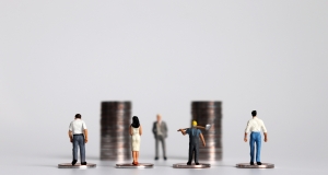 small people figurines standing in front of two piles of coins with their backs to the camera