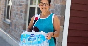 woman holding a case of bottled water