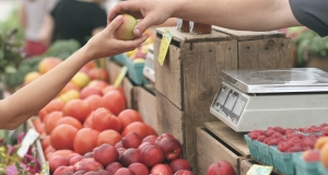 Someone handing an apple over to be weighed