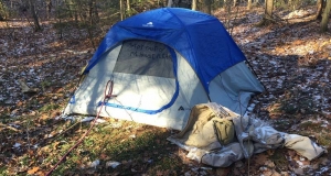 A tent in a city park with the words 'stay out of my home please'