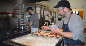 two people making meals in a community kitchen