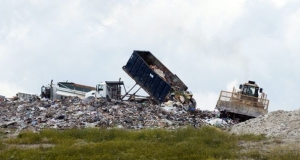 a dump truck adds another load to a pile of garbage