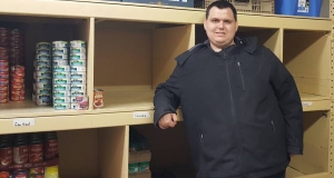 Man standing next to shelves in the food bank