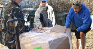 3 people unwrapping a pallet of food 