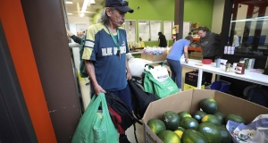 Man standing next to a farm bin of melons 