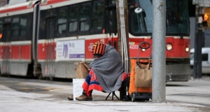 homeless person sitting on a sidewalk