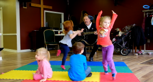 four young children dancing on a colourful mat 