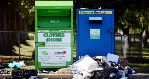 Two large non-profit donation bins with debris around them