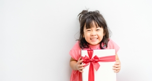 Young girl with a big smile, holding a present with a red bow